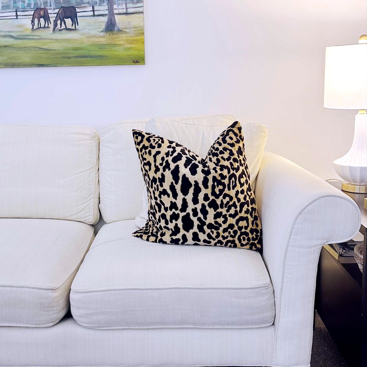 A therapy room at our Mount Pleasant office: a cream sofa with a leopard-print pillow, a lamp, and a painting of horses in a pasture